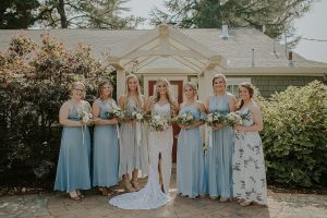 Califonia-bride-with-her-bridesmaids-they-wear-blue-while-she-wears-the-Dreamers-and-Lovers-Penelope-Lace-Dress-with-Open-Back-and-Front-Slit